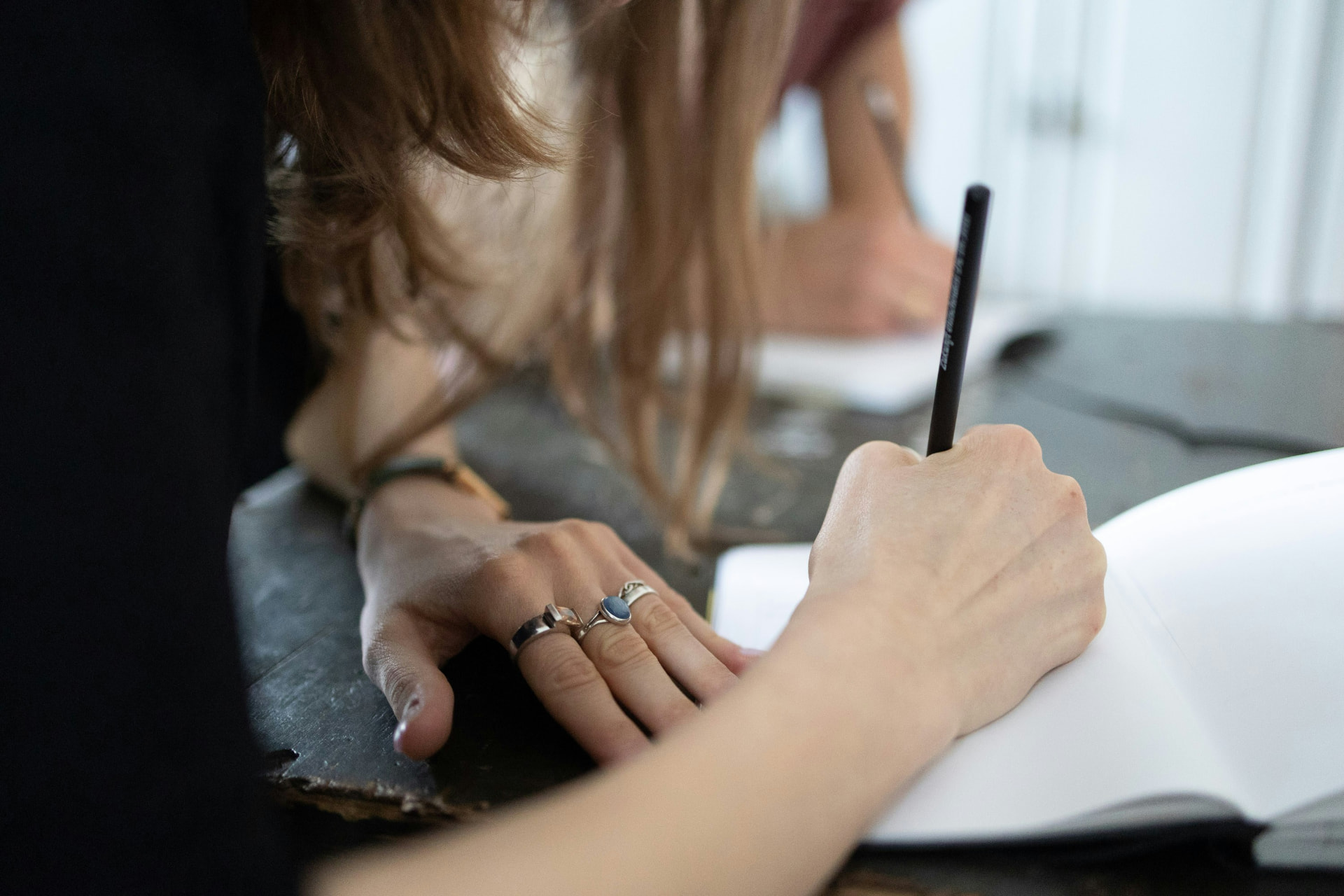 Person schreibt mit einem Stift in ein aufgeschlagenes Buch